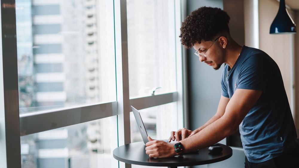 A developer working at a laptop by a window