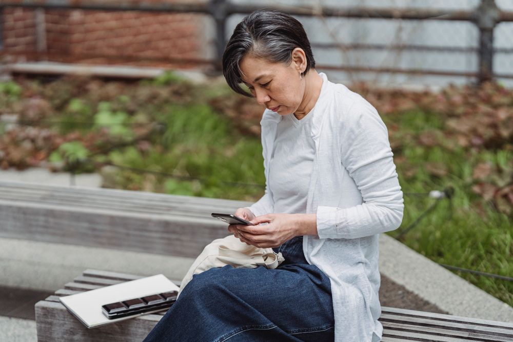 A visitor using a phone on a bench